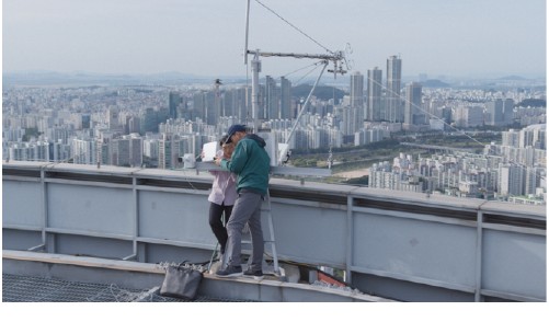 Researchers check equipment on a rooftop overlooking Seoul.